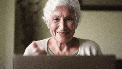 une mamie souriante avec le pouce en lère devant son ordinateur